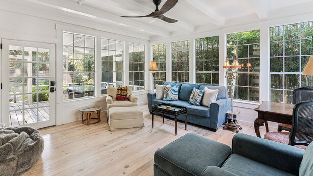 A spacious living room with a blue sofa, a wooden coffee table, and a ceiling fan. - Renovated Cottage w/New Heated Swimming Pool at East Beach's 6th St. Access (Saint Simons Island)