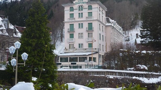 A multi-story building with a sign reading "LES SAPINS" on top. - Cozy T2 bis with Wi-Fi, 100m from center, sleeps 6, ski & bike storage (Mont-Dore)