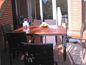 Relax on the patio with a meal or a good book, surrounded by a brick wall and a glass door leading to the adjacent room.