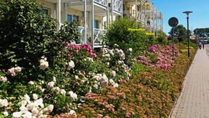 Hotel amb diversos balcons, un camí pavimentat i una gran varietat de plantes florides.