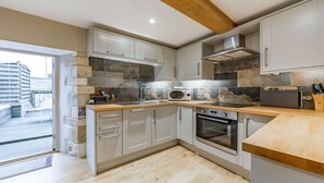 A modern kitchen with grey cabinets, a built-in oven, a microwave, and a wooden countertop. - Stylish two bedroom family friendly holiday Apartment in Stow-on-the-Wold - Church View Apartment (Cheltenham)