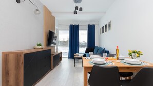 Un espacio habitable moderno con comedor, sofá, televisión y vistas al exterior.