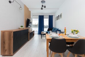 Un espace de vie moderne comprenant un coin repas, un canapé, un téléviseur et une vue sur l’extérieur.