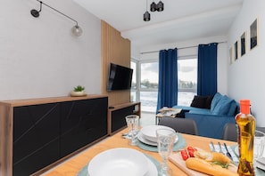 Une chambre d’hôtel moderne dotée d’un coin repas, d’une télévision, d’une grande fenêtre avec des rideaux et offrant une vue sur l’extérieur.