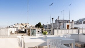 A rooftop terrace with a table and chairs, a potted plant, and a view of a cityscape. - Charming apartment on several levels, located in a renovated period building, of which it retains fascinating evidence in the internal architecture. The flat is ideally located, outside the ZTL but a few steps from the historic center of Ostuni, in an ar (Ostuni)
