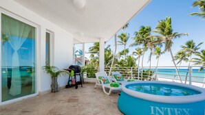 A balcony with a pool, lounge chairs, and a grill. - Punta Cana Condo for Rent (Punta Cana)