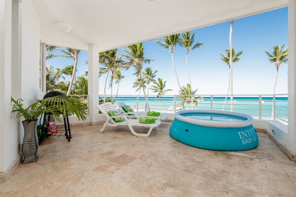 Ein überdachter Außenbereich mit Pool, Liegestühlen und Blick auf den Ozean.