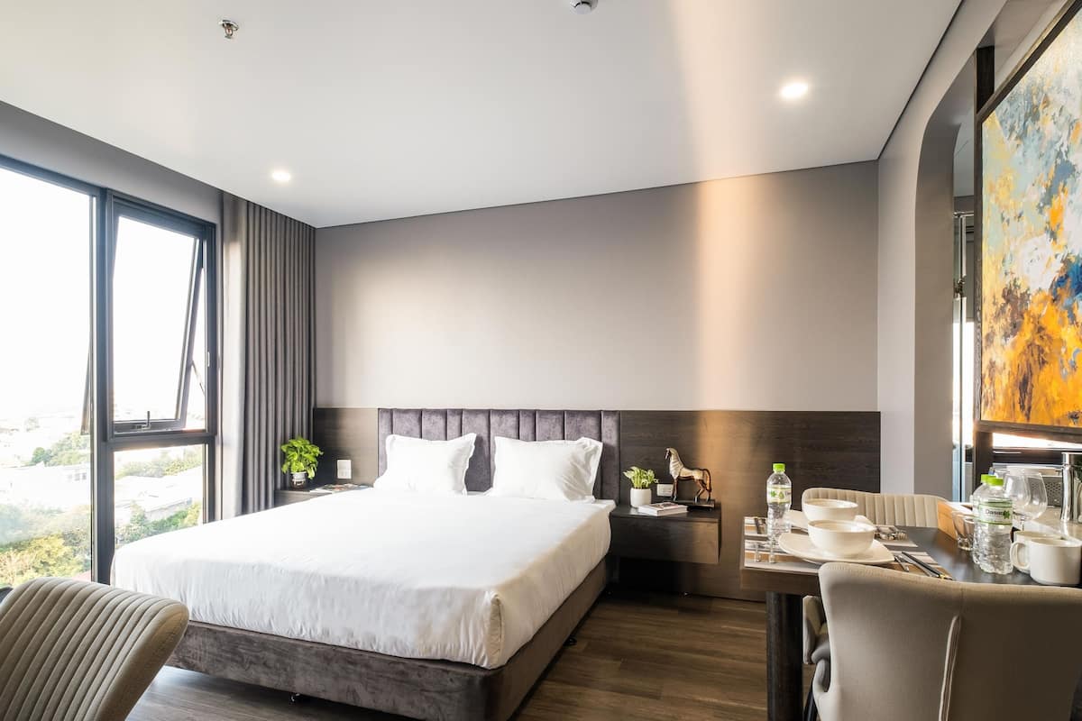 Ett modernt hotellrum med en stor säng, ett skrivbord med en stol och en matplats.