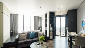 A modern living room with a sofa, a coffee table, and a dining area with a table set for two.