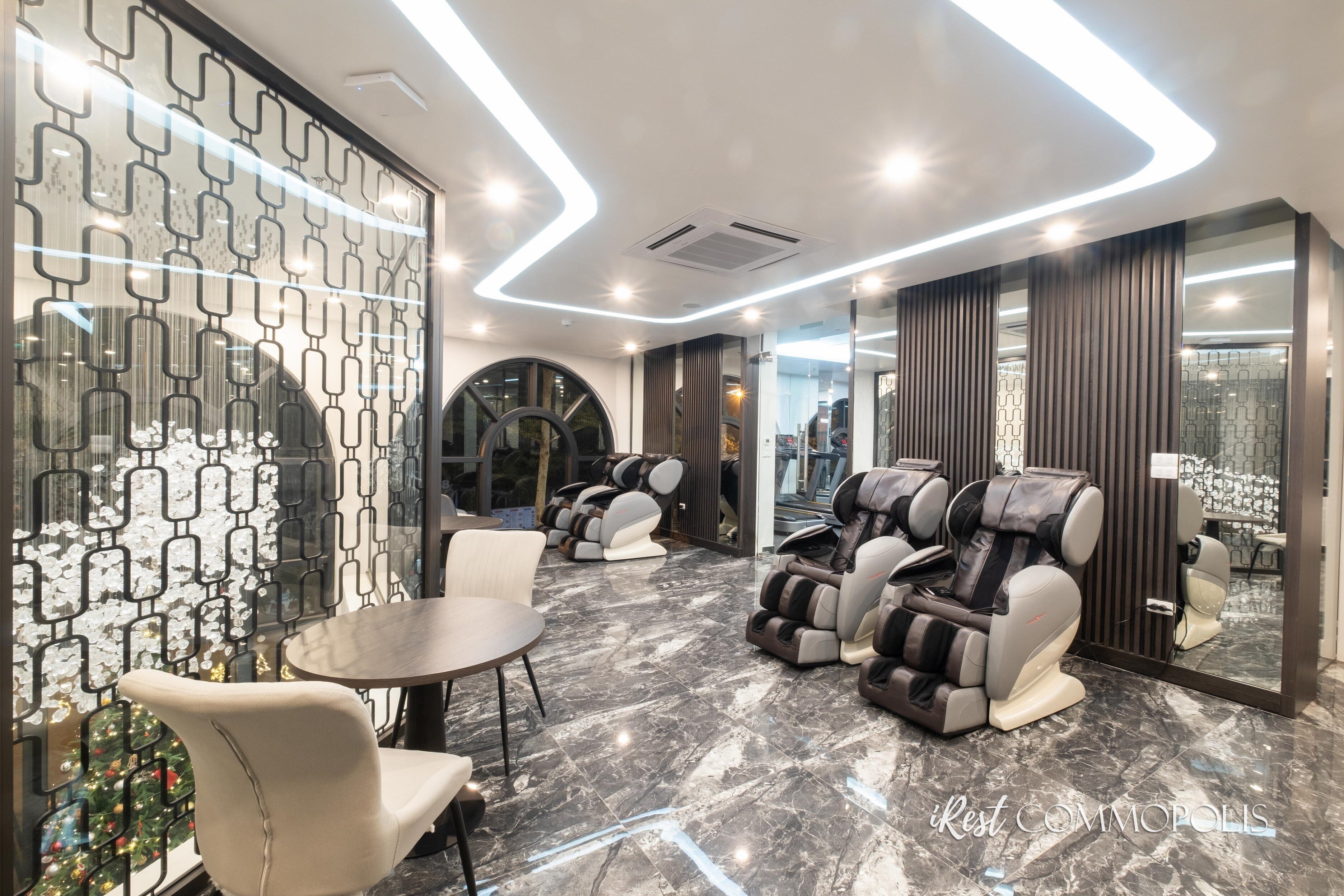 A modern spa area with massage chairs, a small table, and a decorative wall with geometric patterns.