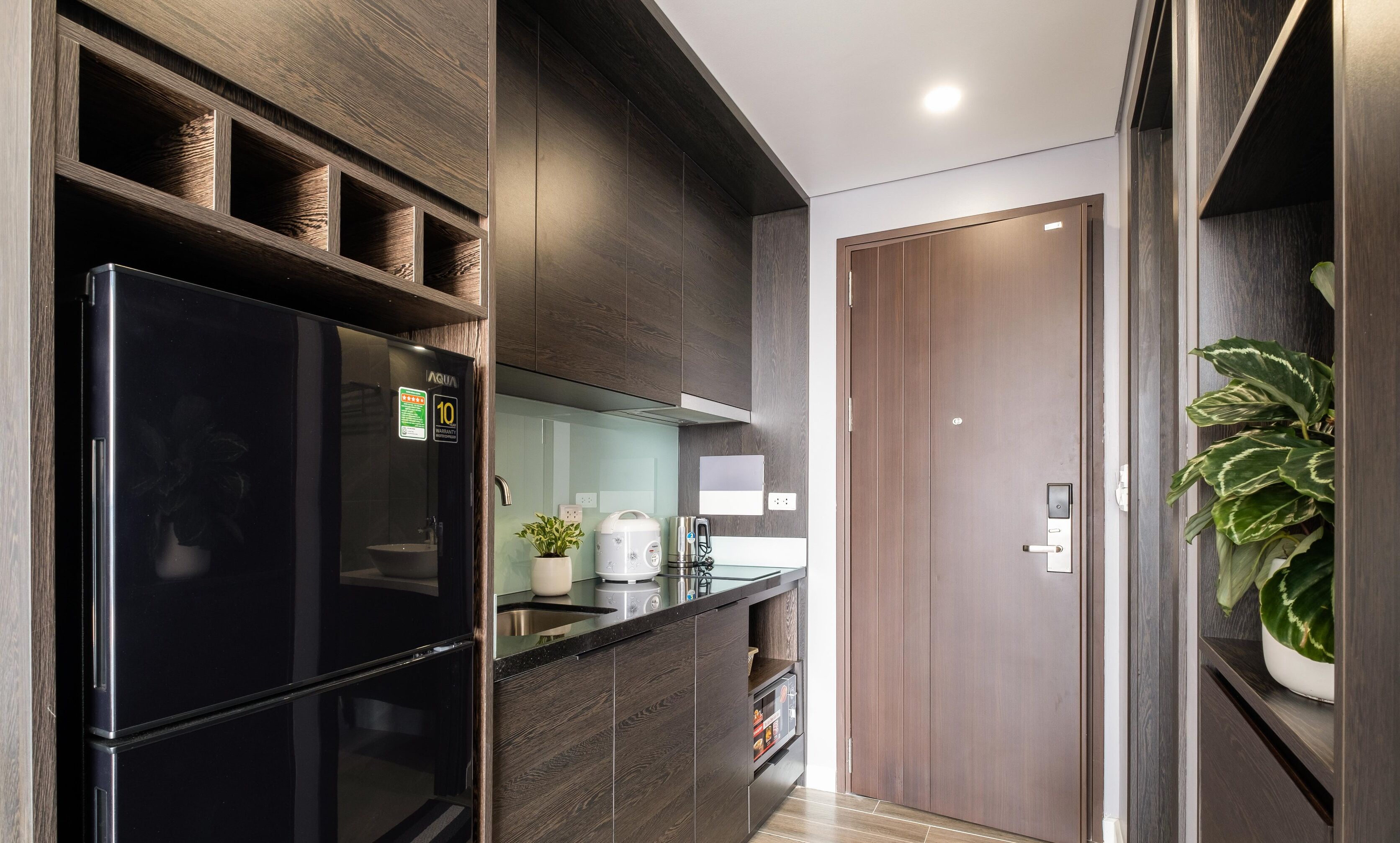 A modern kitchen with a black refrigerator, wooden cabinets, and a built-in oven.