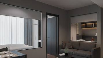 A modern hotel room with a large window, a sofa, a small table, and a mirror reflecting the room.