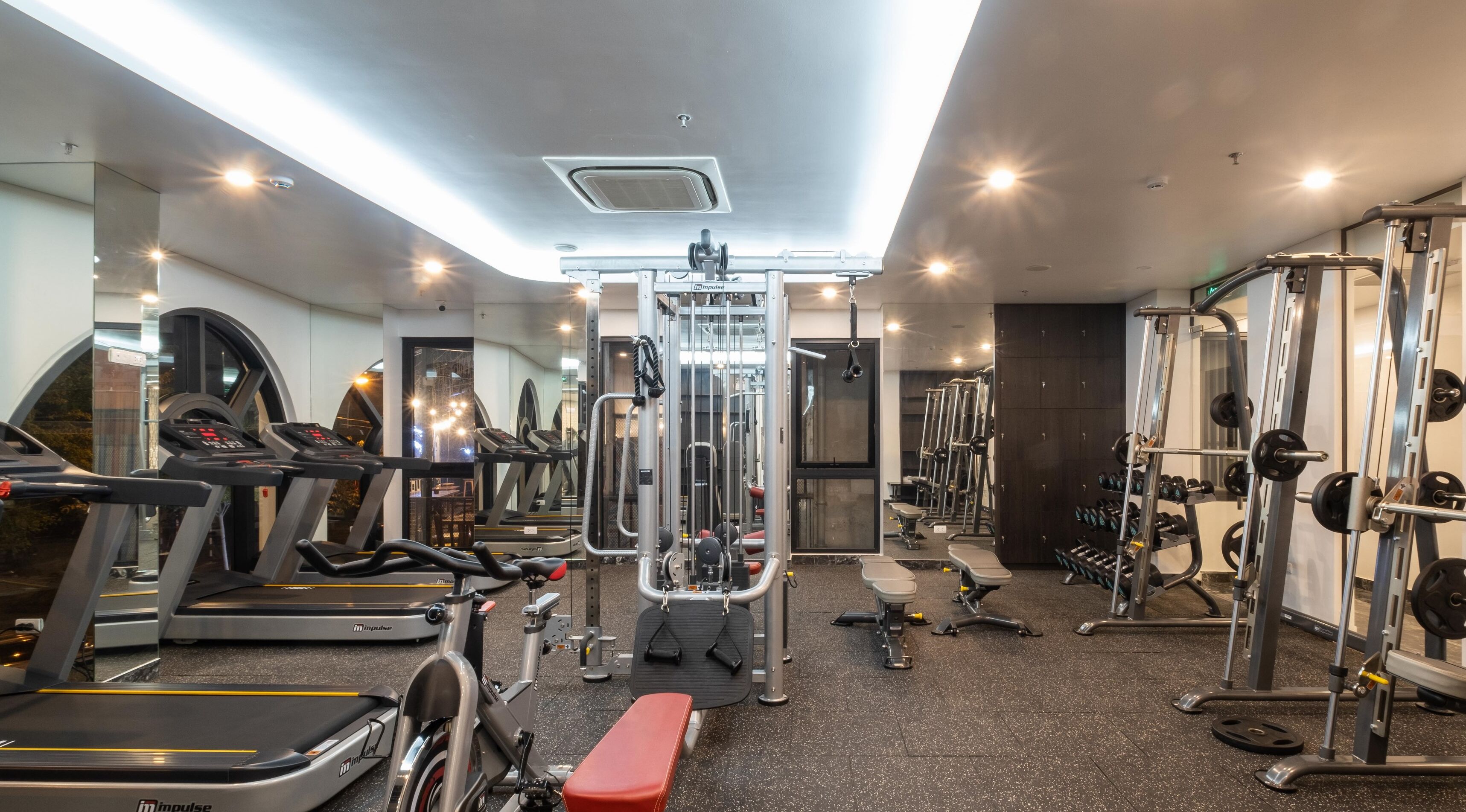 A modern gym with treadmills, a weight machine, and free weights.