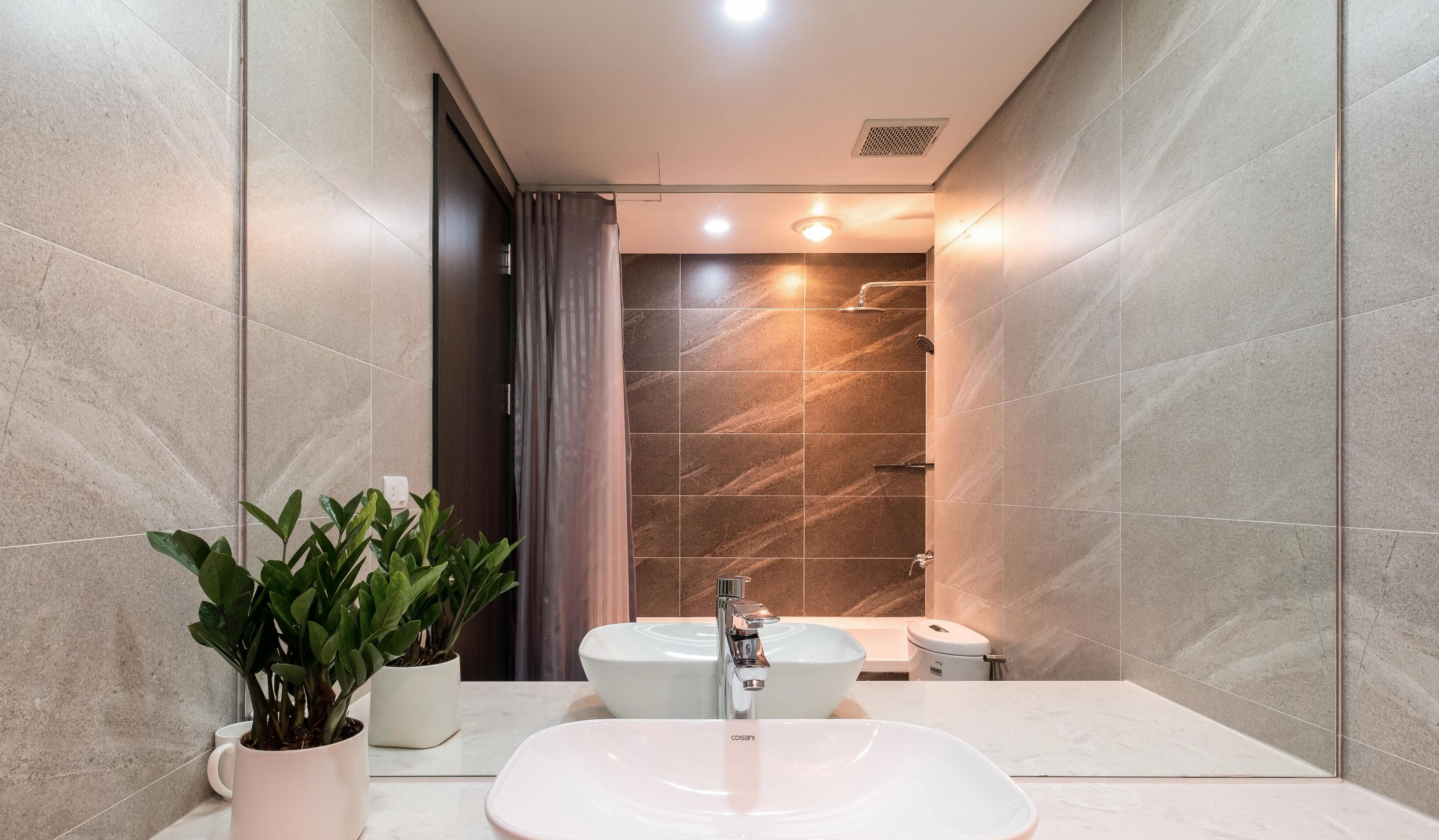 Un bagno moderno con un lavandino ampio, due specchi e una zona doccia.