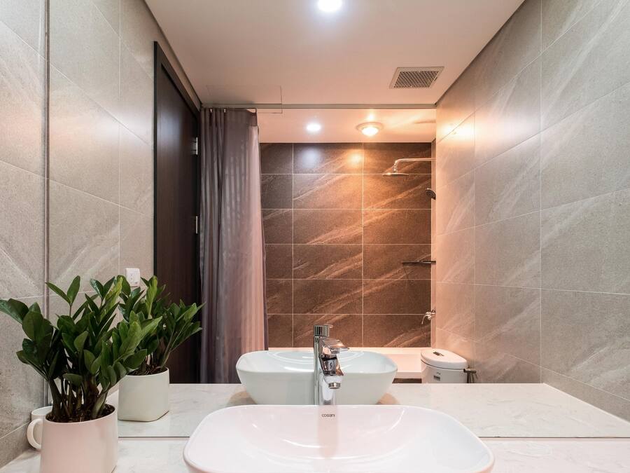 Un bagno moderno con un lavandino ampio, due specchi e una zona doccia.