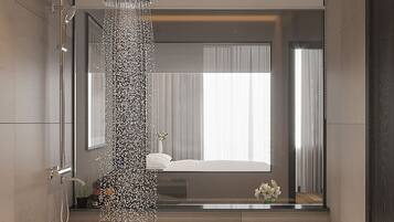 A modern bathroom with a bathtub, a shower, and a large mirror reflecting a bedroom with a bed and curtains.