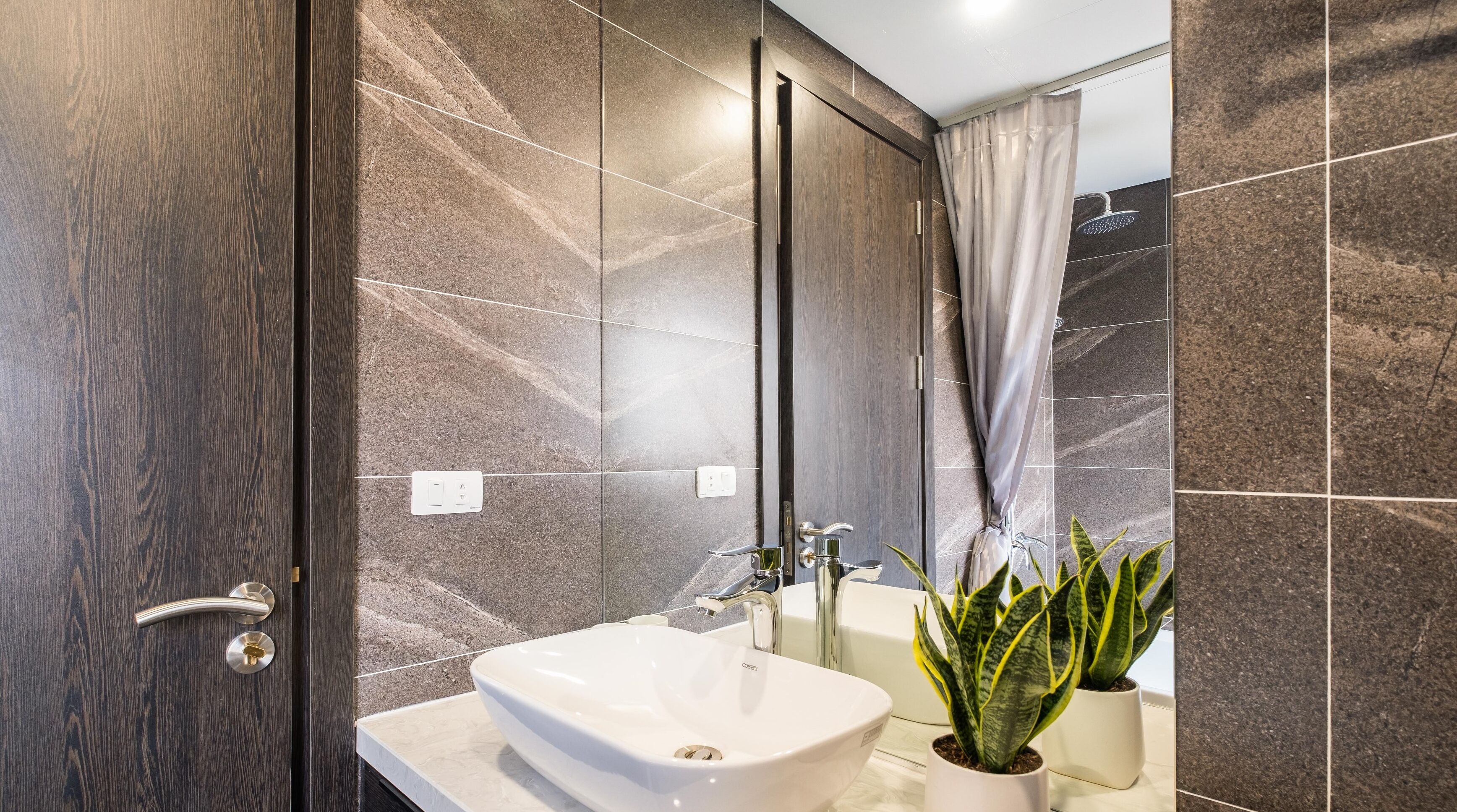 A modern bathroom with a white sink, a mirror, and a shower.