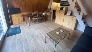 Un intérieur chaleureux en bois, comprenant un coin repas, une cuisine et un escalier.