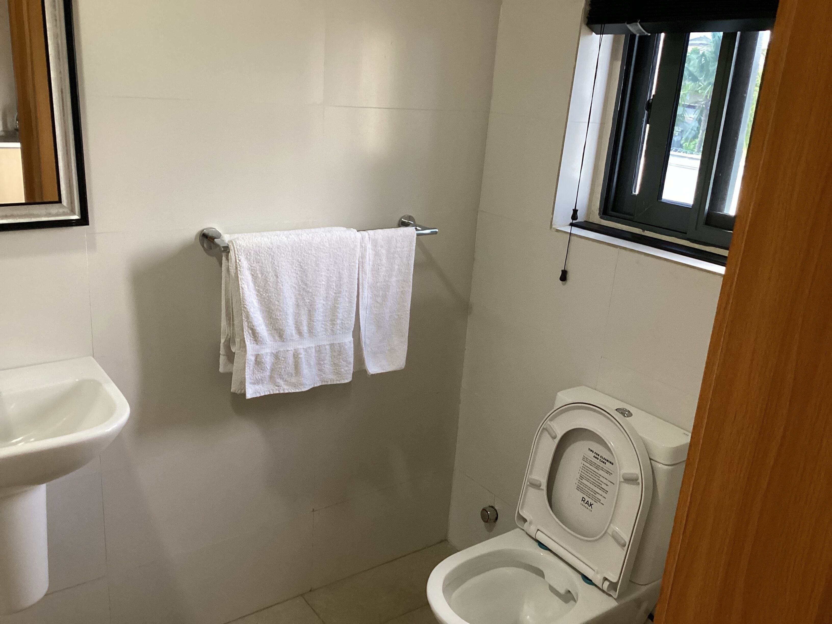 Une salle de bain équipée de toilettes, d’un lavabo et d’un porte-serviettes.