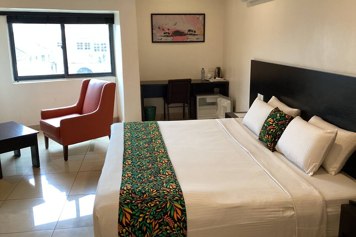 A hotel room with a bed, a desk, a chair, and a window.