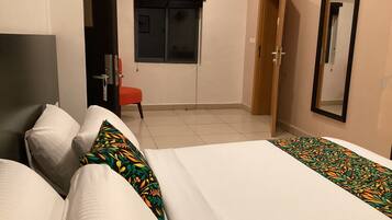Habitación de hotel con dos camas, una silla, un ventanal y una puerta.