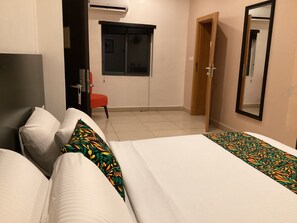 Une chambre d’hôtel avec deux lits, une chaise, une fenêtre et une porte.
