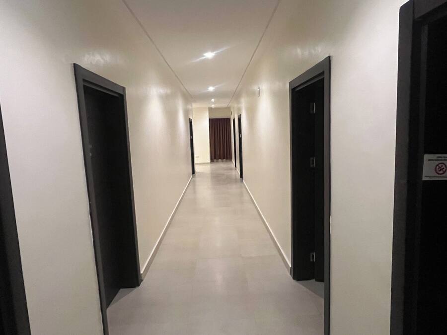 Un pasillo de hotel con puertas a ambos lados, piso de baldosas y un cartel en la puerta derecha.