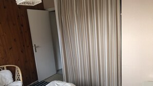 Une chambre à coucher avec un lit, une chaise, une porte et un rideau.