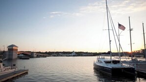 Satamassa on laivoja, silta ja pieni rakennus, jonka katolla liehuu lippu.