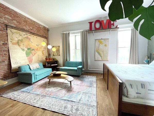Ein gemütliches Zimmer mit einer großen Karte an der Wand, einem Bett, einem blauen Sofa und einem Couchtisch.