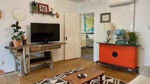 Un salon avec un téléviseur, un meuble rouge, un lustre et une carte accrochée au mur.