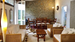A cozy room with wicker furniture, a stone wall, and a large window. - A very special villa (Sardegna)