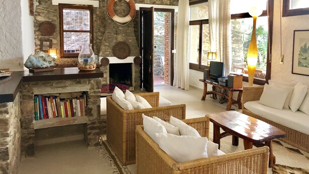 A rustic room with stone walls, a fireplace, wicker furniture, and a television. - A very special villa (Sardegna)