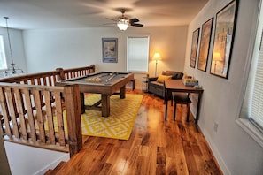A room with a pool table, a ceiling fan, a sofa, a lamp, and framed pictures on the wall. - Escape to Windy Mountain Dreams in Todd, NC—a cozy chalet for 8 with stunning views! (Todd)