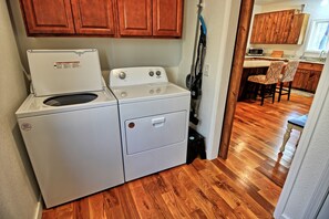 A compact laundry area with a front-loading washer and dryer, wooden cabinets, and a wooden floor. - Escape to Windy Mountain Dreams in Todd, NC—a cozy chalet for 8 with stunning views! (Todd)