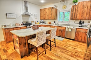 A kitchen with wooden cabinets, a stainless steel range, a microwave, and a coffee maker. - Escape to Windy Mountain Dreams in Todd, NC—a cozy chalet for 8 with stunning views! (Todd)