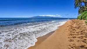 A beach with clear blue water, a sandy shore, and a mountain in the background. - Remodeled, Ground floor studio at The Mahana #102 (Lahaina)