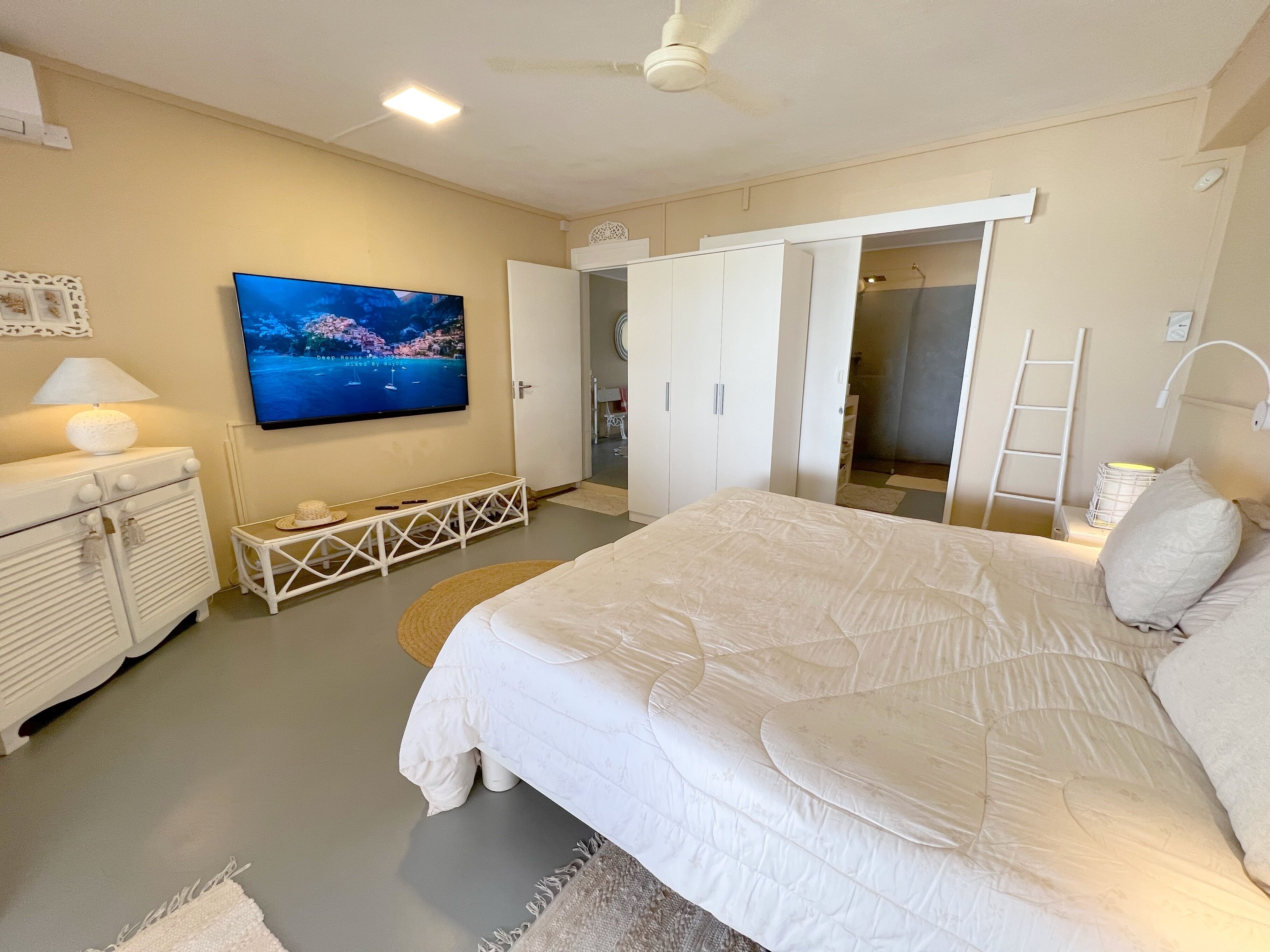 Una camera da letto con un letto, una televisione, un armadio e una ventola a soffitto.
