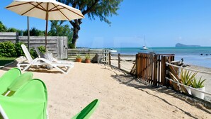 A beachside lounge with lounge chairs, a wooden fence, and a view of the ocean. - Beachfront MEERENA, 2 bedroom cottage with Jacuzzi in Calodyne (Calodyne)
