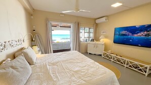 A bedroom with a large bed, a television, and a view of the beach. - Beachfront MEERENA, 2 bedroom cottage with Jacuzzi in Calodyne (Calodyne)
