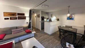 Un salon moderne avec un canapé, une table à manger et une cuisine en arrière-plan.
