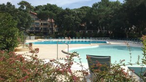 Une piscine entourée de verdure et un bâtiment doté de nombreux balcons.