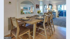 A dining area with a wooden table set for four, surrounded by chairs. - Rehoboth 1st floor, End Unit Condo w/Pools & 5 Minute Bike Ride to Beach (Rehoboth Beach)
