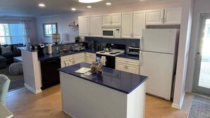 A modern kitchen with white cabinets, a central island, and a built-in microwave. - Rehoboth 1st floor, End Unit Condo w/Pools & 5 Minute Bike Ride to Beach (Rehoboth Beach)