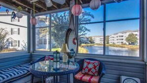 A sunroom with a view of a river, a ceiling fan, and a table with chairs. - Rehoboth 1st floor, End Unit Condo w/Pools & 5 Minute Bike Ride to Beach (Rehoboth Beach)