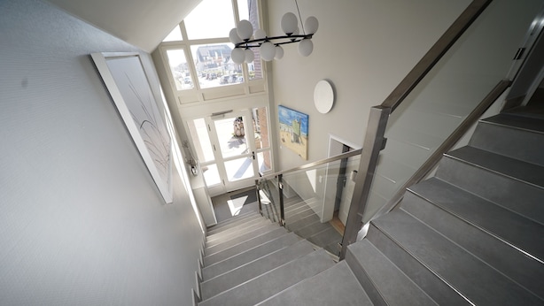 A modern staircase with glass railings and a view of the outside. - Strandvilla Wohnung Strand-lodge (Sylt)