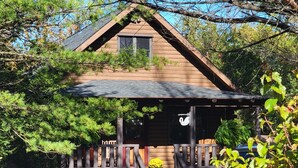 A wooden cabin with a porch, surrounded by trees and plants. - Cozy log cabin in Lake Community.  (Athens)