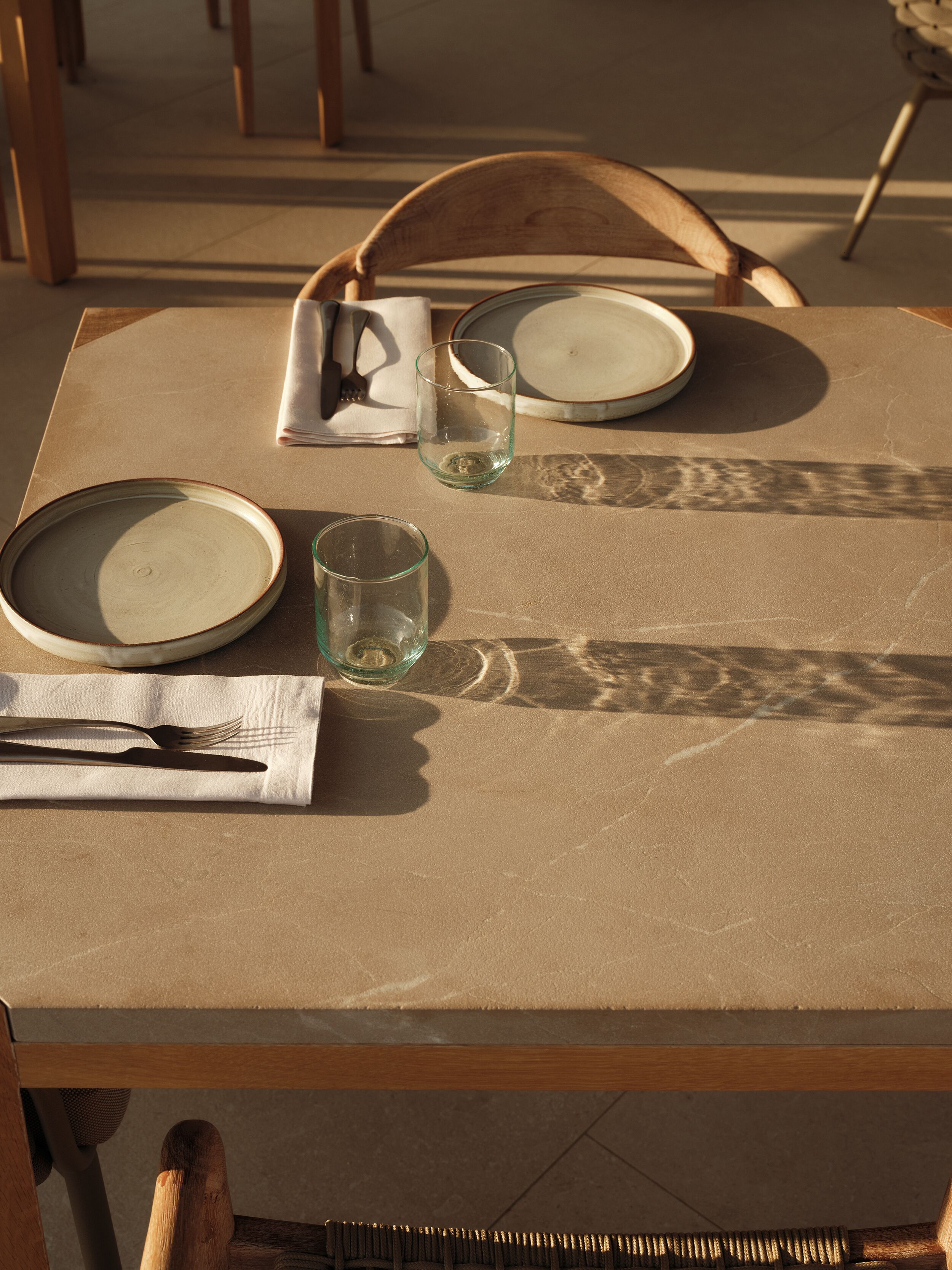 A table set with plates, a glass, and cutlery, with chairs around it.