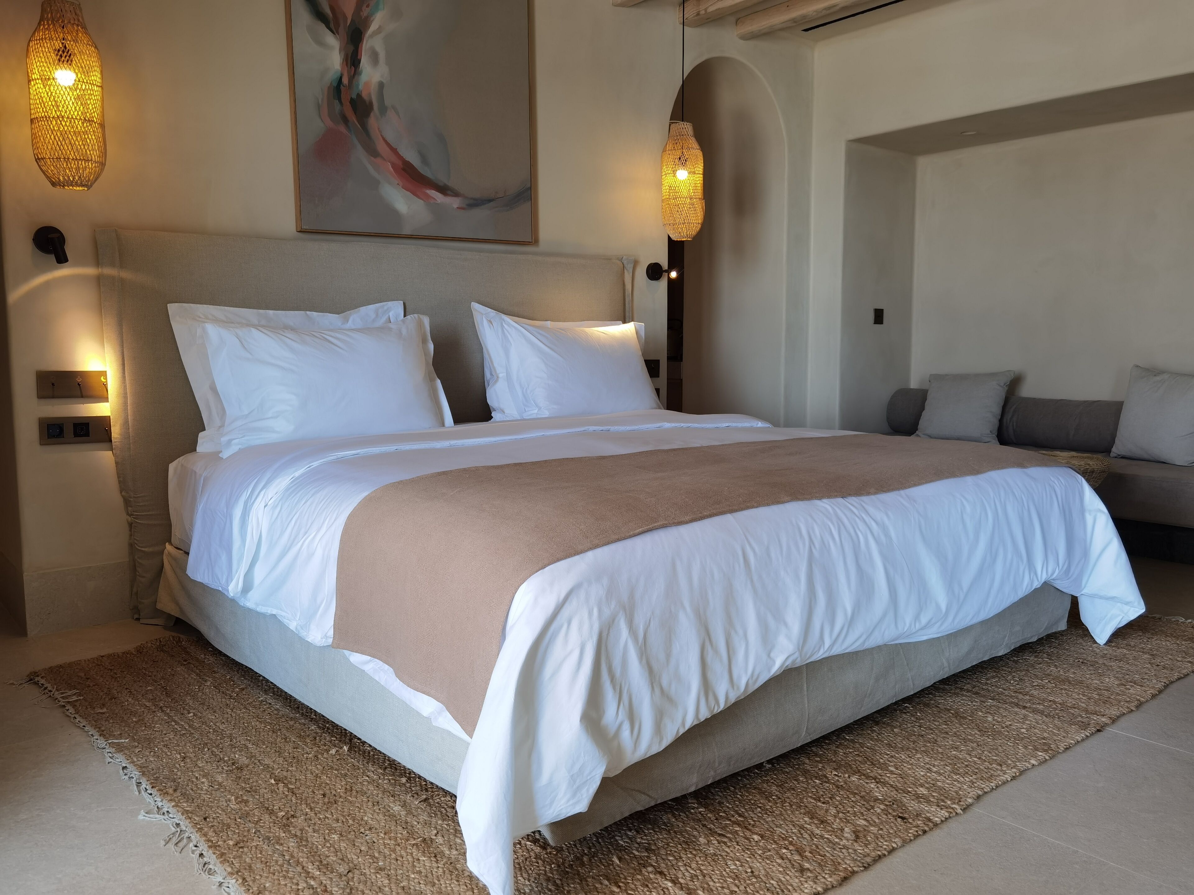 Een moderne slaapkamer met een groot bed, twee nachtkastjes en een bank.