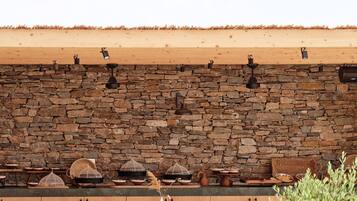 Un espacio de comedor al aire libre con pared de piedra, mesa y sillas de madera.